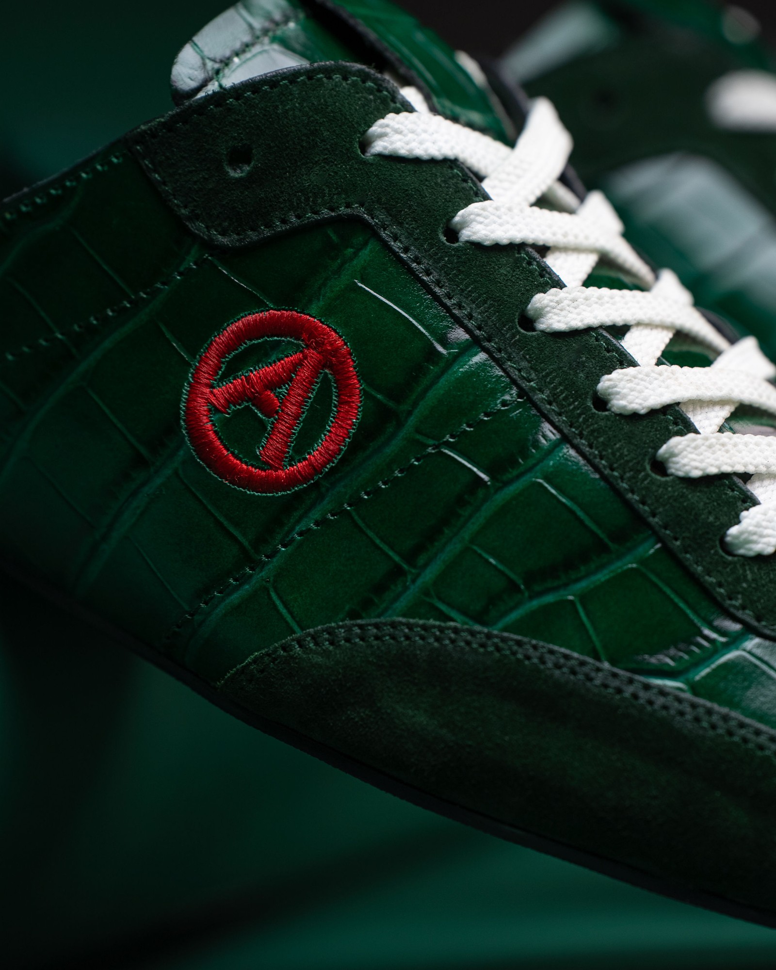 Macro of the red embroidered A on Eko Goose green croc-embossed leather